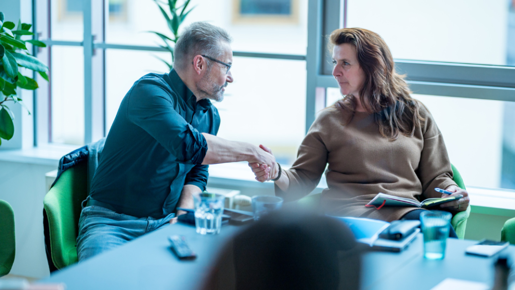 Man and woman at table shaking hands