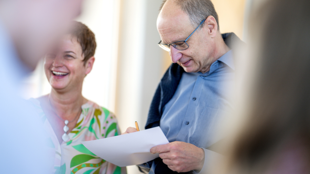 Man writing on paper, woman laughing happily