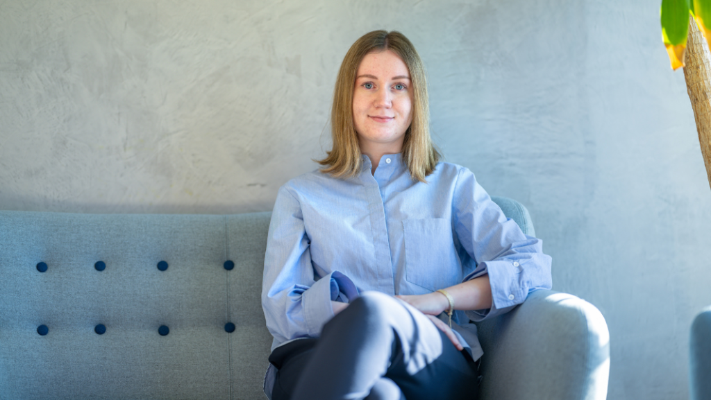 Young woman in blue blouse on grey sofa