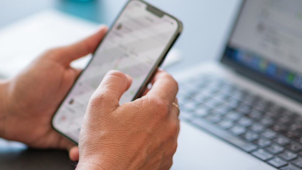 Hand mit Mobile Phone und Laptop
