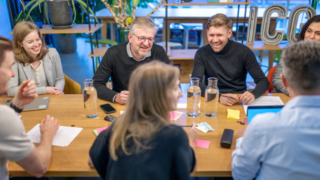 Lachende Menschen an einem Tisch in einer Besprechung