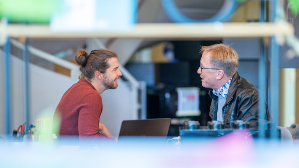 Zwei Männer, im Gespräch durch Regal pgotographiert