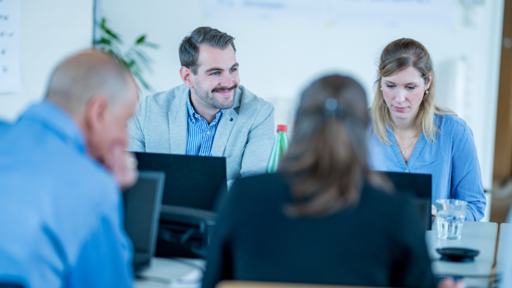 4 Personen mit Laptops an Tisch