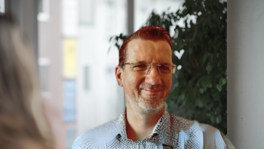 Markus Weigl, Mann im Hemd und Brille vor Fenster und Pflanze