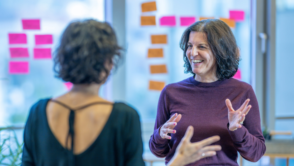 Lächelnde Frau im Gespräch vor Fenster mit Pflanzen