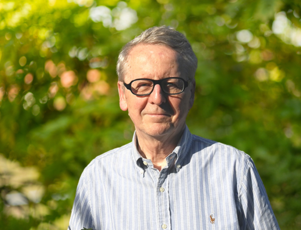Mann mit Brille vor grünem HIntergrund – unscharfer Baum