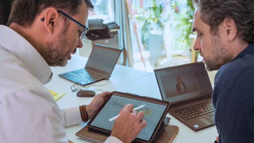 Zwei Männer vor Laptop im Gespräch