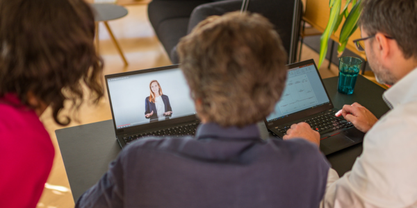 Drei Personen vor Laptop, die Tutorial ansehen